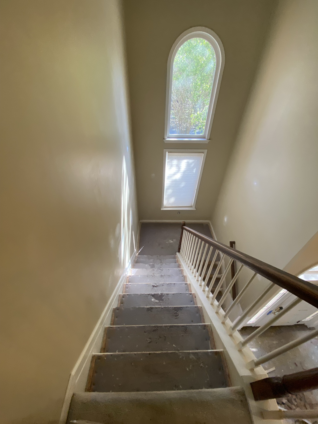 Staircase before — worn carpet, beige walls and an arched window