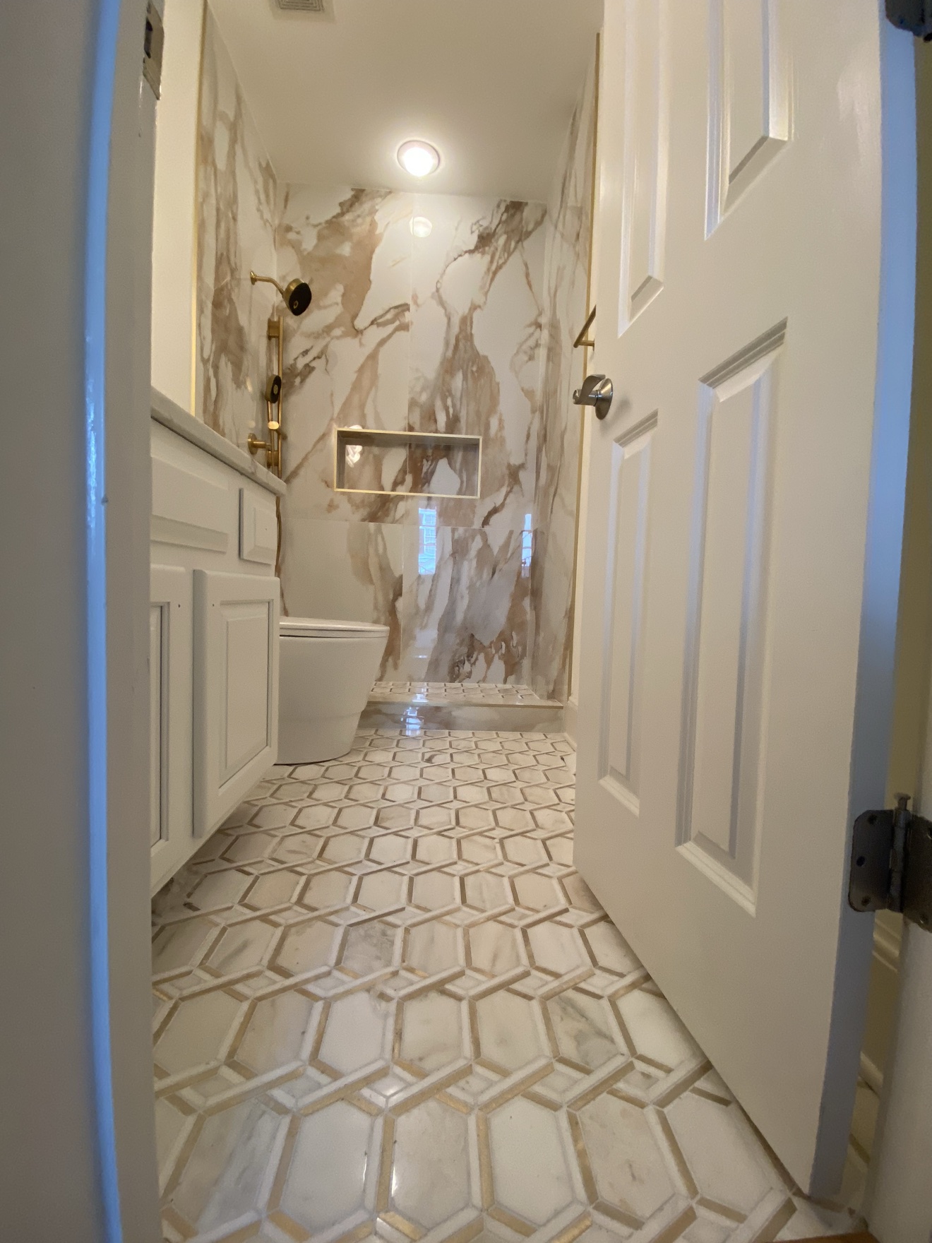 Bathroom finished with marble-look tile and gold fixtures