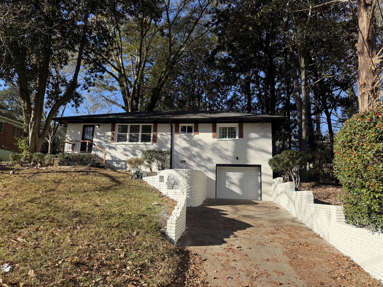 East Point home with its red brick painted white, repaired white retaining walls and a clean driveway