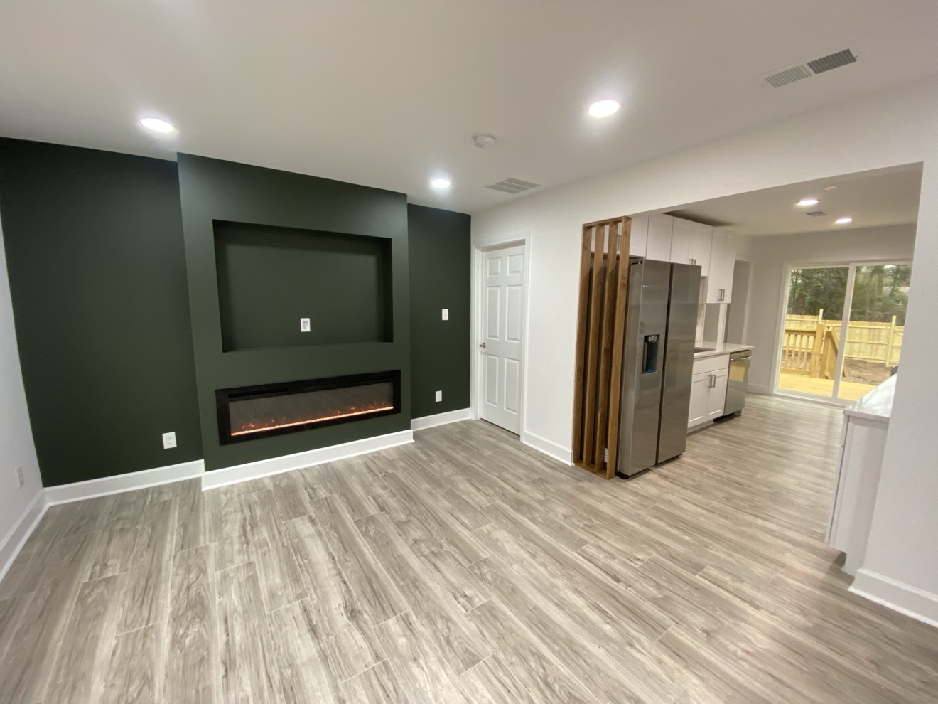 Living room with a deep green accent wall and built-in fireplace
