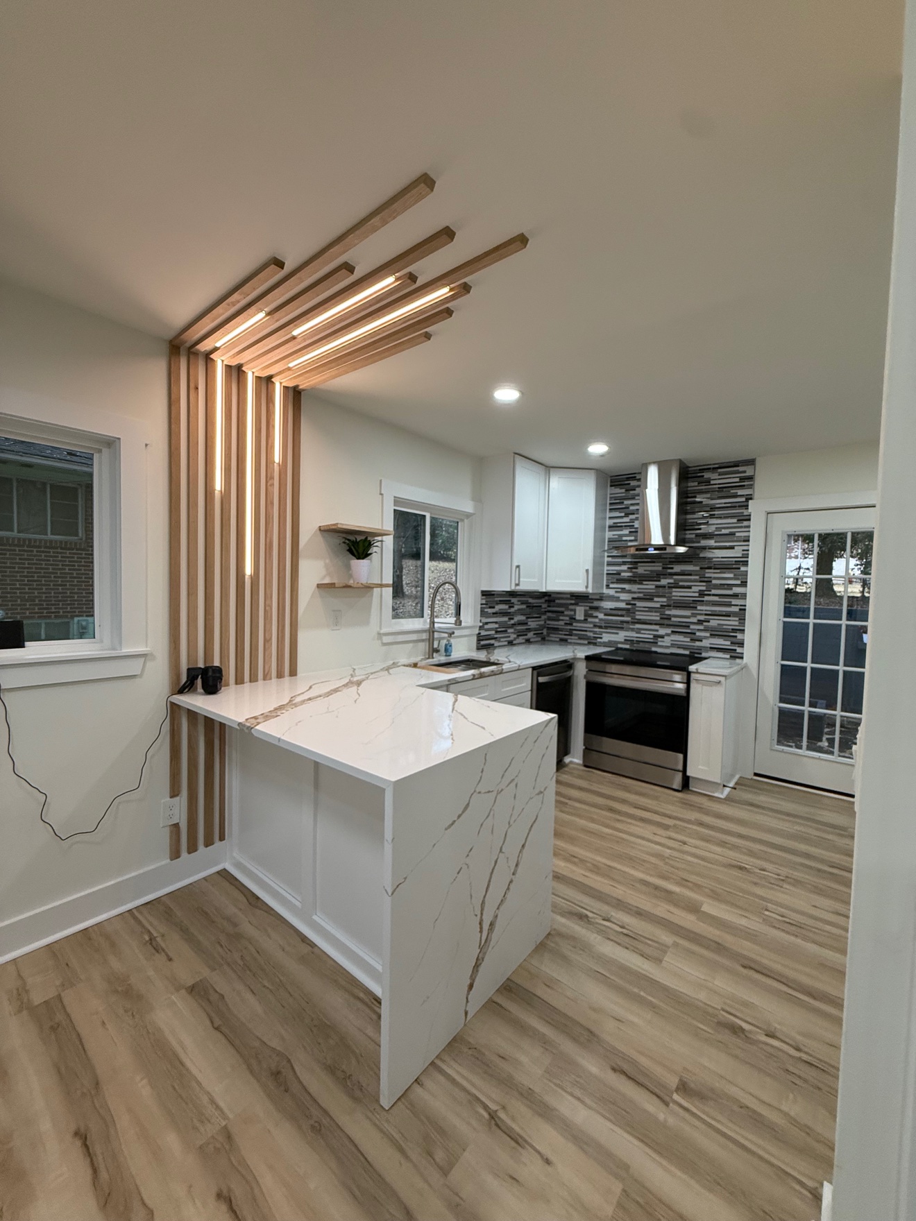 Kitchen with a light wood slat feature wall with built-in lighting and a waterfall island